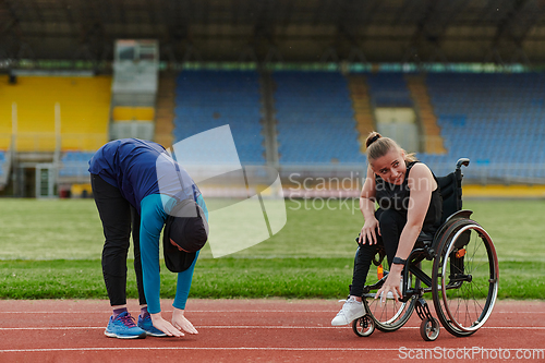 Image of Two strong and inspiring women, one a Muslim wearing a burka and the other in a wheelchair stretching and preparing their bodies for a marathon race on the track