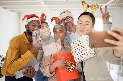 Image of Business people, Christmas selfie and happy staff with present, peace sign or celebration for diversity at party. Men, women and photography for funny xmas memory, friends or gift for social network