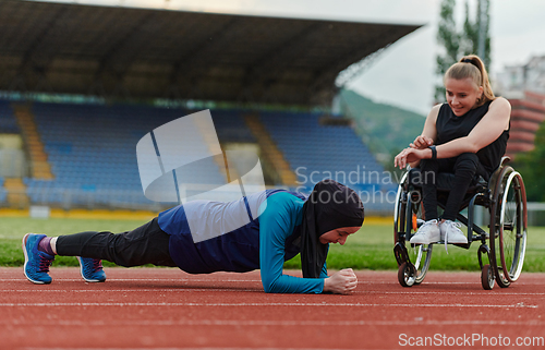 Image of Two strong and inspiring women, one a Muslim wearing a burka and the other in a wheelchair stretching and preparing their bodies for a marathon race on the track