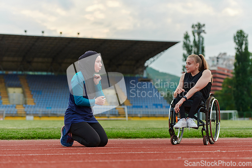 Image of Two strong and inspiring women, one a Muslim wearing a burka and the other in a wheelchair stretching and preparing their bodies for a marathon race on the track