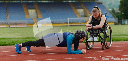 Image of Two strong and inspiring women, one a Muslim wearing a burka and the other in a wheelchair stretching and preparing their bodies for a marathon race on the track