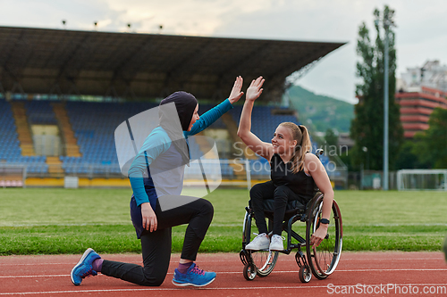 Image of Two strong and inspiring women, one a Muslim wearing a burka and the other in a wheelchair stretching and preparing their bodies for a marathon race on the track