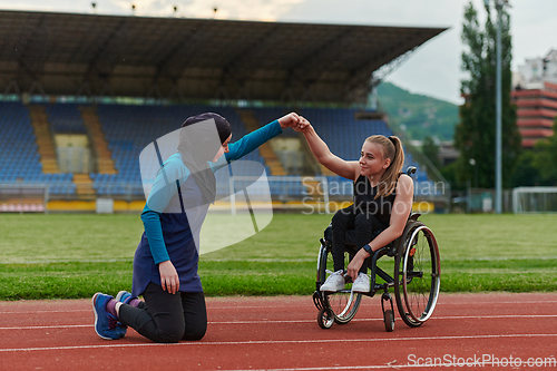 Image of Two strong and inspiring women, one a Muslim wearing a burka and the other in a wheelchair stretching and preparing their bodies for a marathon race on the track