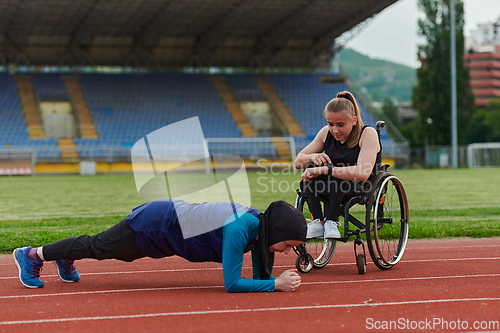 Image of Two strong and inspiring women, one a Muslim wearing a burka and the other in a wheelchair stretching and preparing their bodies for a marathon race on the track