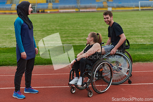 Image of A woman with a disability in a wheelchair talking after training with a woman wearing a hijab and a man in a wheelchair