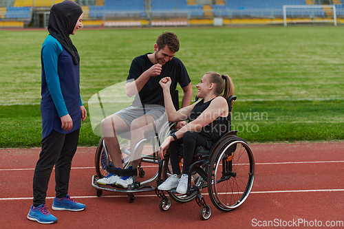 Image of A woman with a disability in a wheelchair talking after training with a woman wearing a hijab and a man in a wheelchair