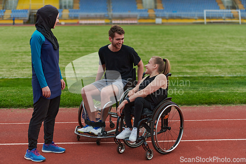 Image of A woman with a disability in a wheelchair talking after training with a woman wearing a hijab and a man in a wheelchair