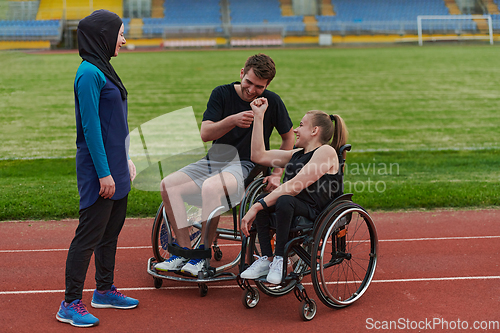 Image of A woman with a disability in a wheelchair talking after training with a woman wearing a hijab and a man in a wheelchair