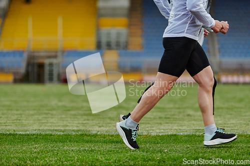 Image of An inspiring and active elderly couple showcase their dedication to fitness as they running together on a lush green field, captured in a close-up shot of their legs in motion.