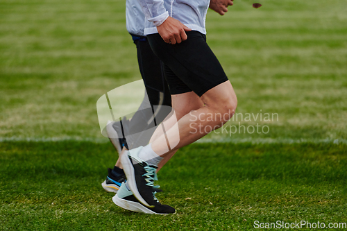 Image of An inspiring and active elderly couple showcase their dedication to fitness as they running together on a lush green field, captured in a close-up shot of their legs in motion.