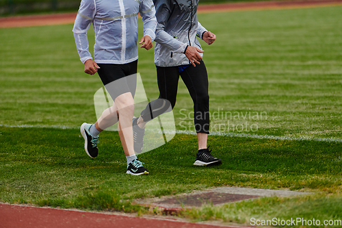 Image of An inspiring and active elderly couple showcase their dedication to fitness as they running together on a lush green field, captured in a close-up shot of their legs in motion.