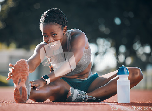 Image of Sports, stretching and exercise with a woman outdoor on a track for running, training or workout. Happy African athlete person at stadium for legs stretch, fitness and muscle warm up or body wellness