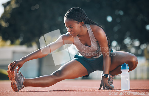 Image of Exercise, sports and a woman stretching outdoor on a track for running, training or workout. African athlete person at stadium for legs stretch, fitness and muscle warm up or body wellness on ground