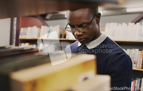 Image of University, student and black man in a library reading and learning on campus for knowledge and education in college. Smart, clever and person doing research with books on a shelf for an exam