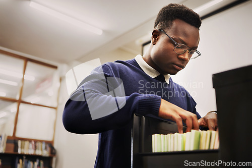 Image of School research, notes and a black man in a library for knowledge, learning or studying. University, scholarship and a young African person or student looking at books for decision or choice