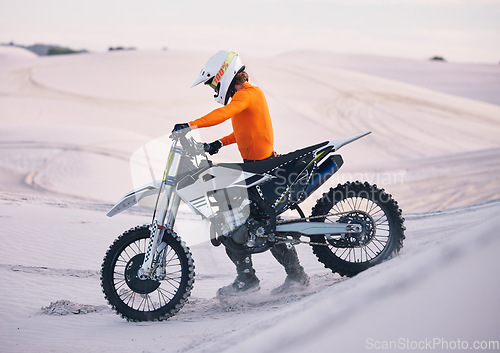 Image of Bike, sand and freedom with a sports man pushing a vehicle in the desert for adventure or adrenaline. Motorcycle, training and dunes with an athlete outdoor in nature for power or active competition