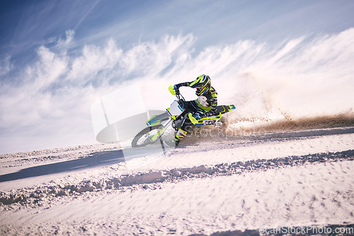 Image of Bike, sky and speed with a man on sand riding a vehicle in the desert for adventure or adrenaline. Motorcycle, training and dust with an athlete outdoor in nature for freedom, power or competition