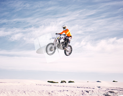 Image of Bike, speed and jump with a man on sand riding a vehicle in the desert for adventure or adrenaline. Motorcycle, training and freedom with an athlete in the sky in nature for power or competition