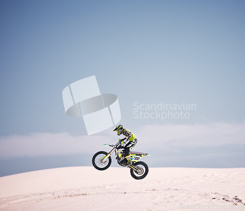 Image of Bike, sky and jump with a man on mockup riding a vehicle in the desert for adventure or adrenaline. Motorcycle, speed and space with an athlete on sand in nature for freedom, power or competition