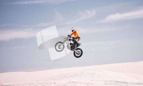 Image of Motorcycle, sky and jump with a man in the desert riding a vehicle for adventure or adrenaline. Bike, speed and training on sand with an athlete in the air in nature for freedom or active competition