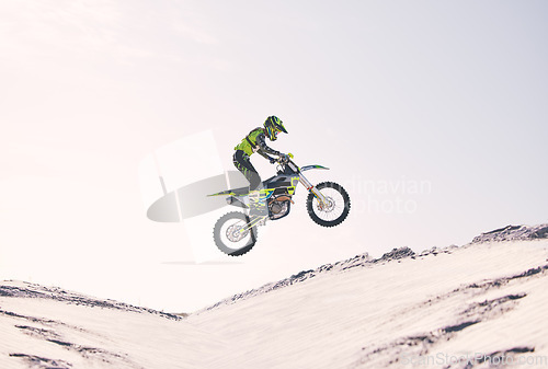 Image of Bike, sand and jump with a sports man riding a vehicle in the desert for adventure or adrenaline. Motorcycle, training and ramp with an athlete outdoor in nature for freedom, power or competition