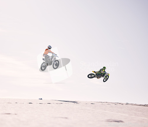 Image of Dune, jump and men on motorbike together for practice, training and extreme sports energy in nature. Professional dirt biking challenge, friends and danger with motorcycle competition on desert hill.