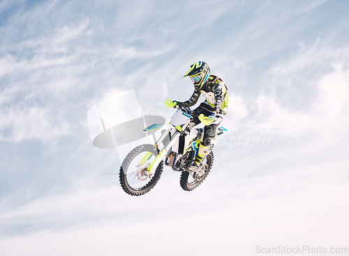 Image of Blue sky, jump and man on motorbike in air for practice, training and extreme sports energy. Professional dirt biking speed challenge, off road adventure and danger at off road motorcycle competition