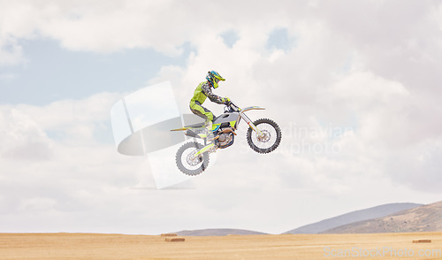 Image of Desert, motorbike cycling and jump for sports, agile driving and off road adventure with mockup space in cloudy sky. Motorcycle, challenge and moving in air for action, fearless talent and sand dunes