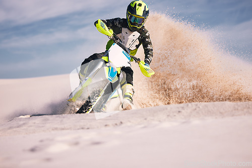 Image of Motorcycle, dust and energy with a sports man riding a vehicle in the desert for adventure or adrenaline. Bike, freedom and training on sand with an athlete outdoor in nature for power or competition