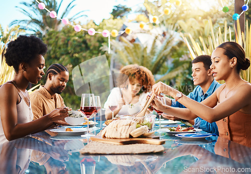 Image of Friends at dinner, party in summer in garden and happy event with diversity, food and wine for bonding together. Outdoor lunch, men and women at table, group of people eating with drinks in backyard