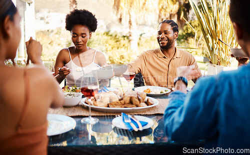 Image of Group of friends at table, eating in garden and happy event with diversity, food and wine bonding together. Outdoor dinner, men and women at lunch, people at party with drinks in backyard in summer.