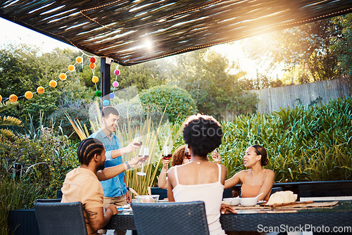 Image of Cheers, friends at dinner in garden at party and celebration with diversity, food and wine at outdoor party. Glass toast, men and women at table, fun people with sunset drinks in backyard together.