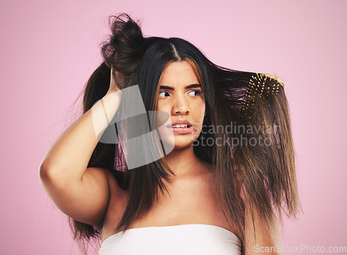 Image of Woman, hair care and studio with brush, tangle and stress with frustrated face by pink background. Girl, model and anxiety with mistake, fail and thinking with beauty, cleaning and cosmetic crisis