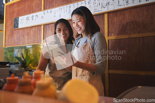 Image of Cafe, tablet and asian women together at counter checking sales, booking or menu for small business. Social media, content marketing and startup restaurant owner with waitress scroll on digital app.