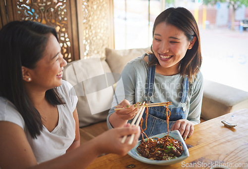 Image of Chopsticks, restaurant and girl friends eating noodles and Asian cuisine at a cafe. Happy, hungry women and plate of food at a Japanese bar with friendship, smile and bonding from meal at a table