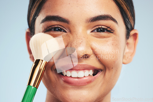 Image of Portrait, happy woman and brush for makeup in studio, apply foundation and glow on blue background. Closeup face of model smile for aesthetic cosmetics, skincare tools and beauty powder for makeover