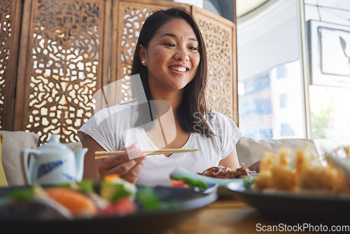 Image of Asian, food and woman at a restaurant eating for dinner or lunch meal using chopsticks and feeling happy for nutrition. Plate, young and person enjoy Japanese cuisine, noodles or diet at a table