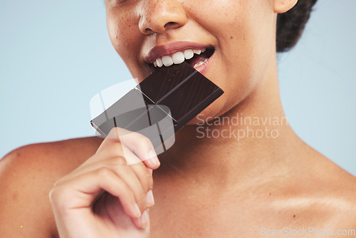 Image of Eating, chocolate and woman in studio with unhealthy, diet or luxury snack on blue background. Sugar, bite and lady model with cocoa candy bar craving, addiction or sweet satisfaction while isolated