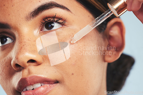 Image of Woman, face oil and serum in studio for beauty of aesthetic skincare, dermatology and makeup on blue background. Closeup of model with dropper for facial cosmetics, hyaluronic acid and clean shine