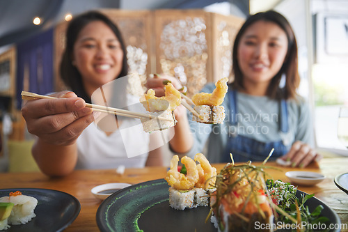 Image of Chopsticks, girl friends and shrimp sushi at a table with salmon and Japanese cuisine food at restaurant. Young women, eating and tempura prawn with fish for lunch and meal on a plate with a smile