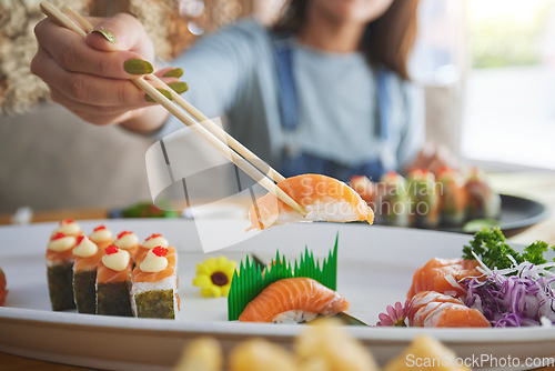 Image of Hands, chopsticks and woman with sushi in restaurant, fine dining and eating in cafe store. Salmon, stick and person on fish, meat and tempura food in plate for lunch, brunch and healthy seafood meal