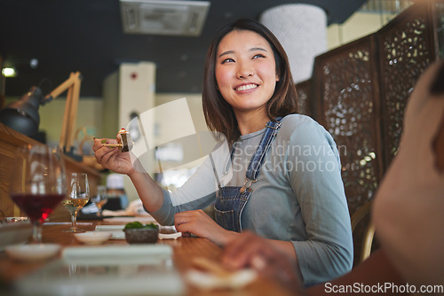 Image of Asian, sushi and woman at a restaurant eating for dinner or lunch meal using chopsticks and feeling happy with smile. Plate, young and person enjoy Japanese cuisine, noodles or diet at a table