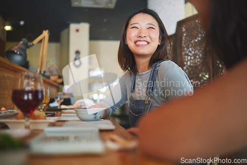 Image of Happy, eating and friends at a restaurant for food, conversation or bonding together. Smile, excited and an Asian girl or women at a cafe for fine dining, talking and hungry at a table with people