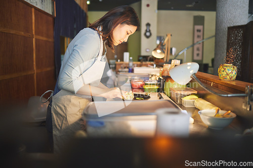 Image of Chinese food, chef and an asian woman in a sushi restaurant to serve a traditional meal for nutrition. Kitchen, cooking or preparation with a happy young employee in an eatery for fine dining cuisine