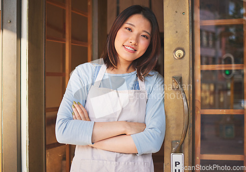 Image of Portrait, waitress and Asian woman with arms crossed at door of restaurant, coffee shop or store. Face, smile and confident barista, happy employee or small business entrepreneur at cafe in Japan