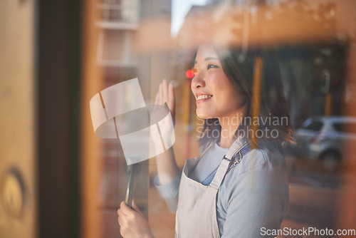 Image of Asian woman, window and door of restaurant to welcome service, small business owner and wave with reflection. Hello from manager, smile and Japanese food cafe startup with happy entrepreneur at work.