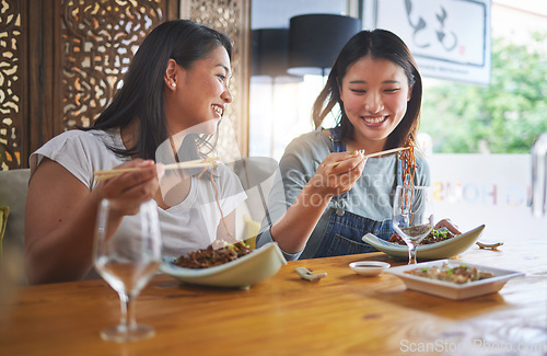 Image of Restaurant, girl friends and lunch with food, noodles and cafe happy from bonding. Asian women, eating and plate together with friendship smile at a table hungry with chopsticks at Japanese bar