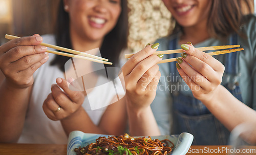 Image of Chopsticks, restaurant and friends hands with noodles and Asian cuisine at a cafe. Happy, hungry women and plate of food at a Japanese bar with friendship, smile and bonding from meal at a table