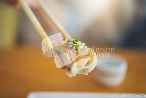 Image of Closeup, protein and chopsticks with dumpling at a restaurant for food, Asian culture or fine dining. Health, hungry and person with dinner, eating lunch or enjoying a fried dish or cuisine at a cafe