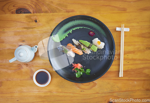 Image of Sushi, food and chopsticks in an asian restaurant from above for fine dining or traditional cuisine. Salmon, menu and seafood with a chinese dish on a table in a local eatery for hunger or nutrition